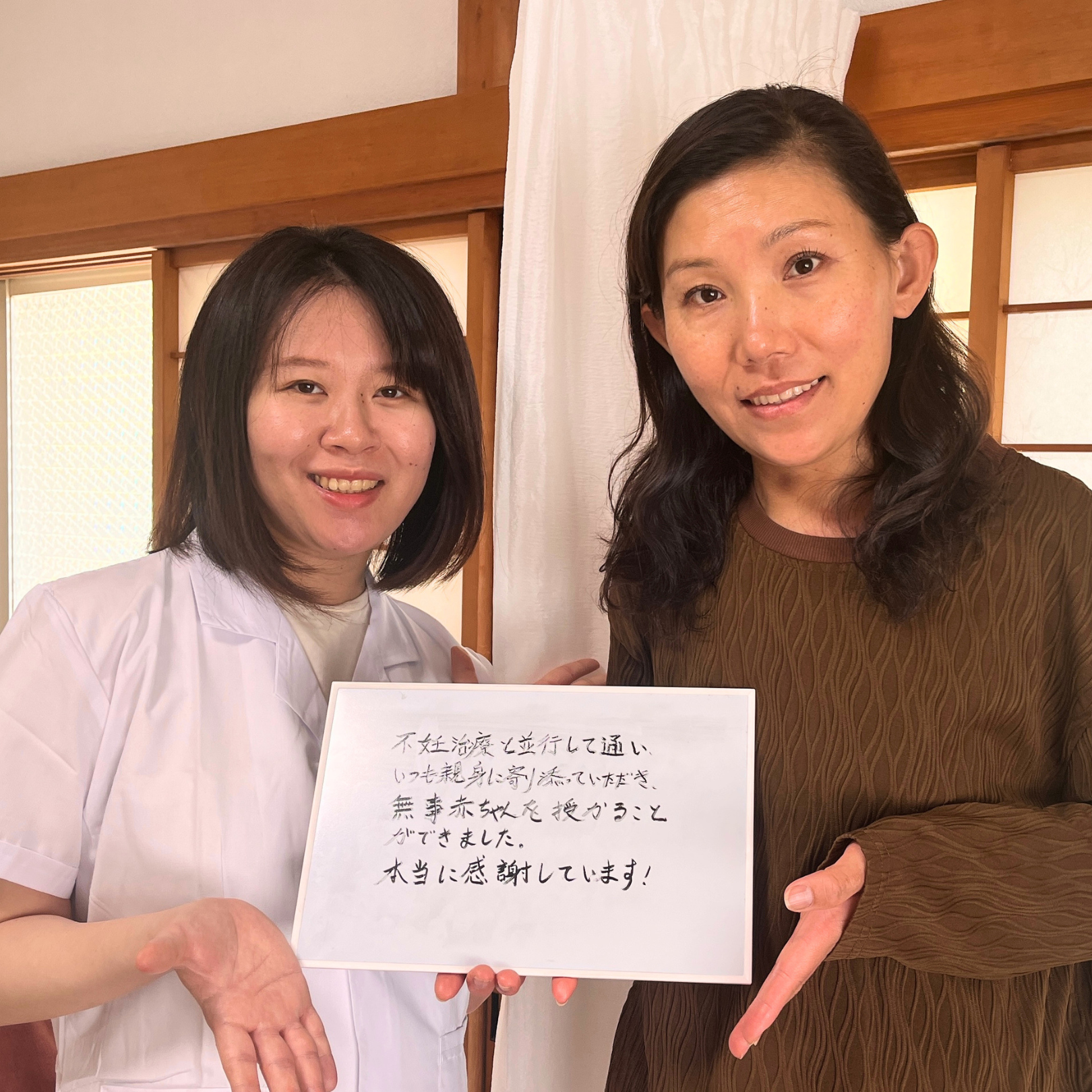 妊活をサポートしてもらったとホワイトボードに記入してくれたお客様と院長 中沢詩文のツーショット写真